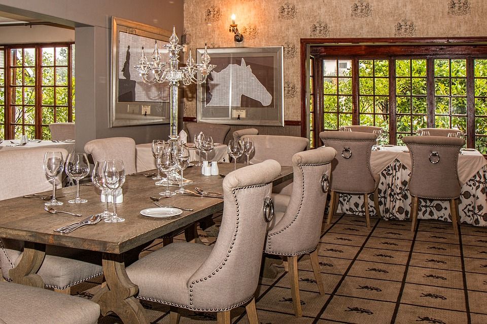 Elegant dining room with a wooden table set for guests, surrounded by upholstered chairs.