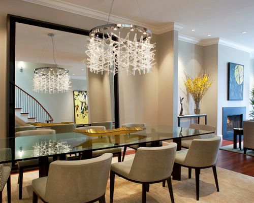 Modern dining room with glass table, upholstered chairs, and a large rectangular mirror.