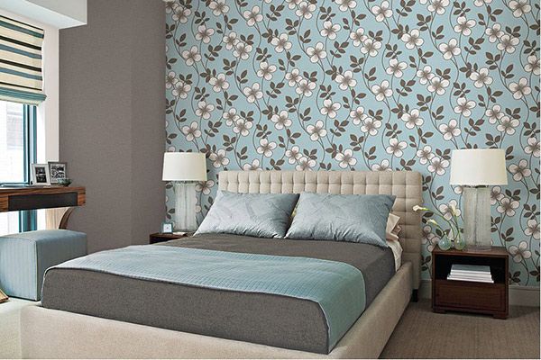 Modern bedroom with a floral patterned accent wall and a neutral bed.
