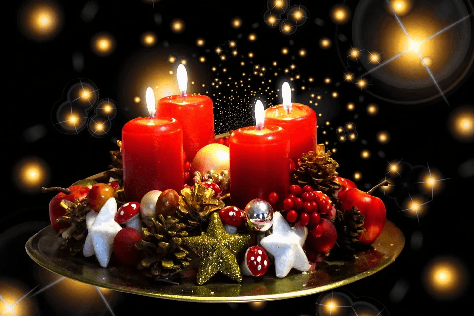 Four lit red candles adorn a festive Advent wreath with berries and pinecones.