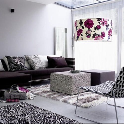 Modern living room with dark grey sectional sofa, patterned rugs, and floral pendant light.