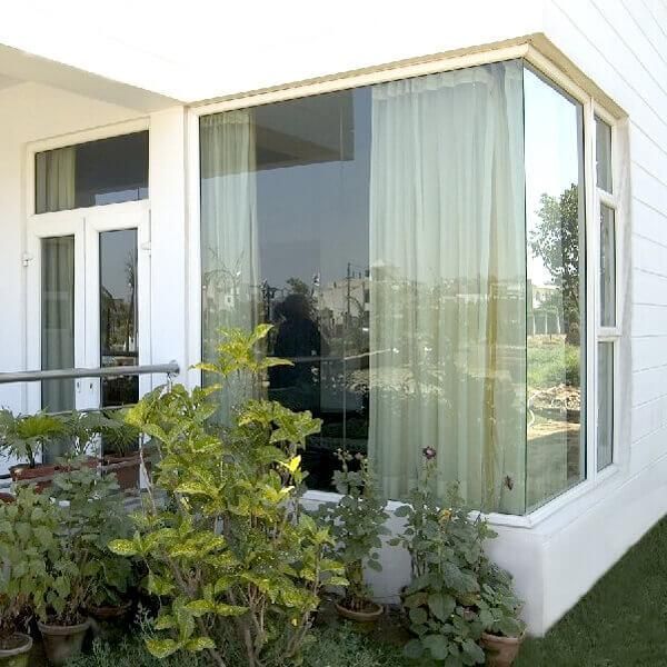 Modern building exterior featuring large glass bay windows and potted green plants below.