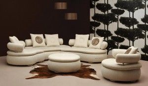 Modern curved cream sectional sofa set with a matching ottoman and single armchair.