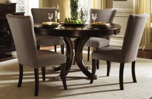 Dark wood round dining table with four upholstered chairs set for a meal.