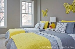 Two twin beds in a grey and yellow bedroom with butterfly wall decor.