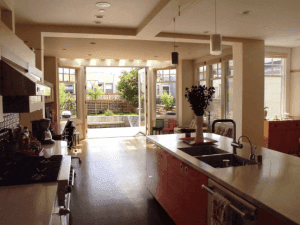 Spacious modern kitchen featuring a red island and bi-fold doors opening to an outdoor patio.