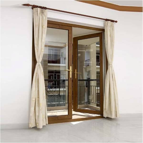 Open brown-framed glass doors with tied-back beige curtains provide access to a balcony.
