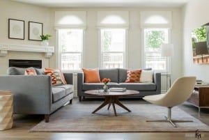 Modern living room with two gray sofas, round coffee table, white armchair, and fireplace.