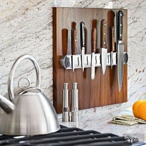 Wooden magnetic knife strip holding various kitchen knives above a stainless steel kettle.