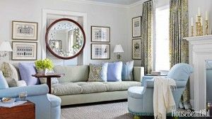 Light-filled living room with a green sofa, blue armchairs, and a round mirror.