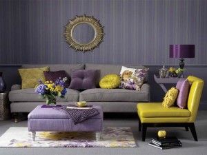 Stylish living room featuring a grey sofa, purple ottoman, yellow chair, and gold sunburst mirror.
