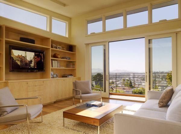 A modern living room with large windows, panoramic city view, and light-colored furnishings.