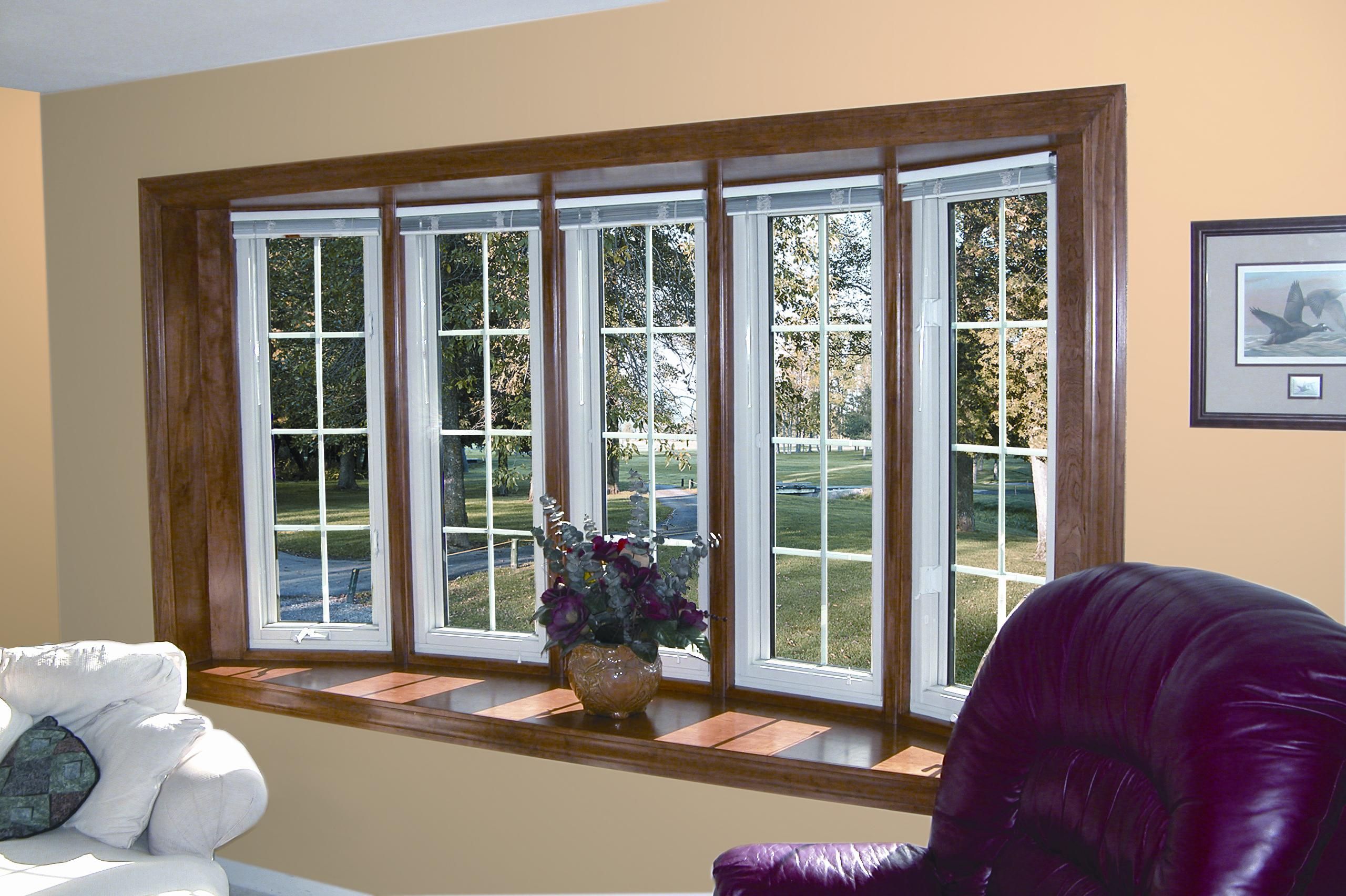 A large bay window with dark wooden trim overlooks a garden with trees.