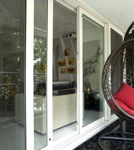 White sliding glass doors reflecting interior, with a wicker hanging egg chair outside.