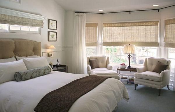 A bright and spacious bedroom with a large bed, neutral decor, and multiple windows.