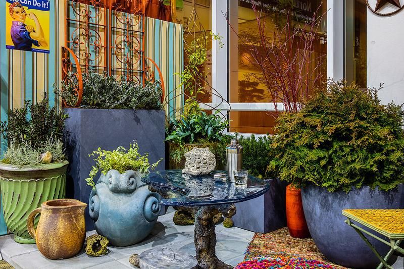 Eclectic outdoor patio featuring diverse potted plants, colorful ceramic pots, and a small glass table.
