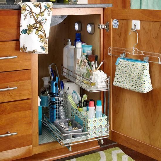 Pull-out two-tier organizer filled with cleaning supplies and toiletries in an open cabinet.