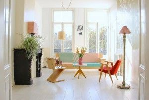 Bright, modern living room with a colorful pastel sofa, mid-century furniture, and large windows.