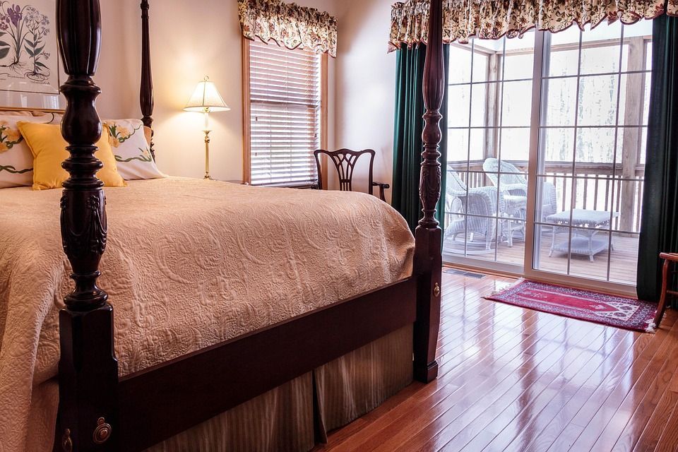 A cozy bedroom with a four-poster bed and a sliding door to a balcony.