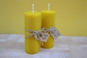 Two yellow honeycomb beeswax candles tied with twine on a yellow background.