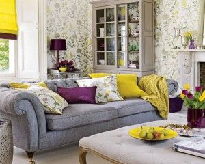 Elegant living room with a grey tufted sofa, yellow and purple accents, and floral wallpaper.