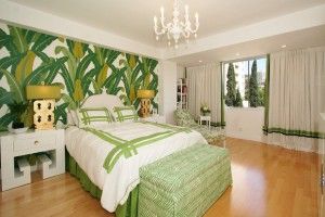 A vibrant bedroom with green banana leaf wallpaper, white bedding, and hardwood floors.