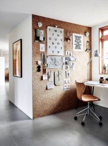 Modern home office with a large, organized cork board wall and desk.