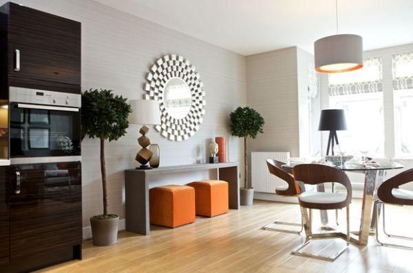 Modern open-plan kitchen and dining room with a sunburst mirror and vibrant orange accents.