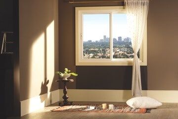 Room with a window overlooking a city skyline, bathed in sunlight.