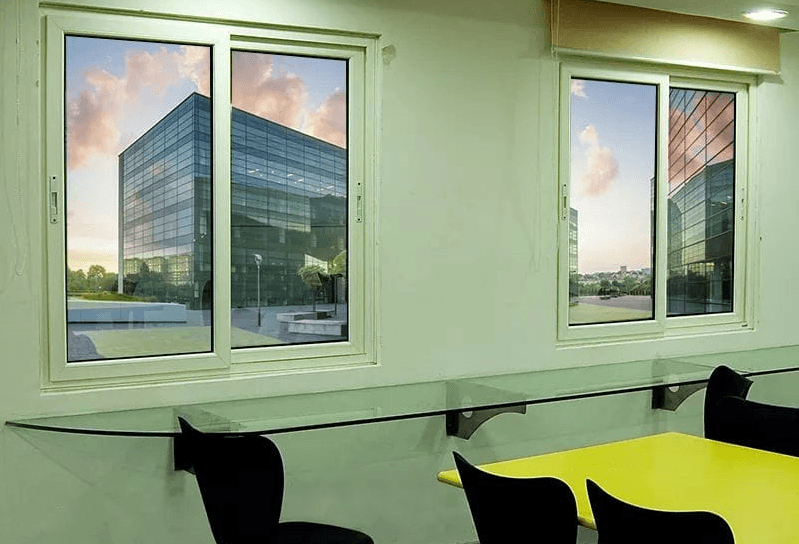 Interior room features two windows reflecting a modern glass building and a glass shelf.