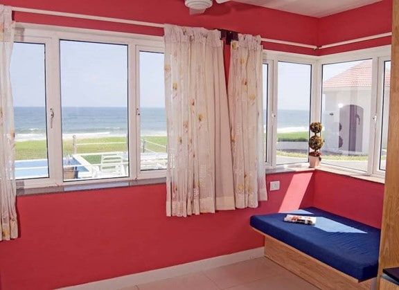 Red room with large windows offering an expansive view of the ocean and beach.