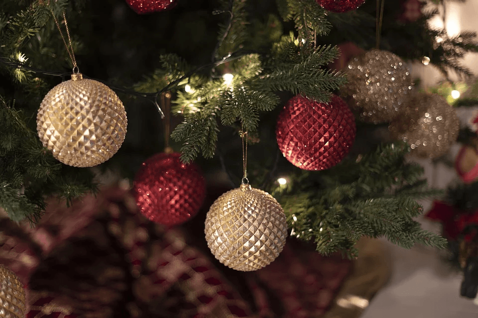 Christmas tree decorated with red and gold textured ornaments and warm white lights.