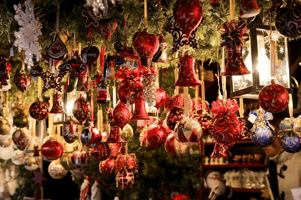 Red and gold Christmas ornaments, including bells and balls, hang from festive greenery.