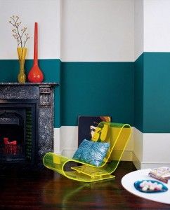Modern living room with teal and white walls, dark fireplace, and a yellow S-shaped chair.