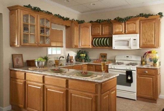 Light wood kitchen featuring a central island, white appliances, and decorative greenery on cabinets.