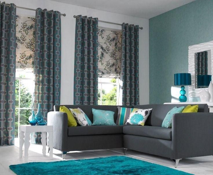 Modern living room with a grey sectional sofa, vibrant teal rug, and patterned curtains.
