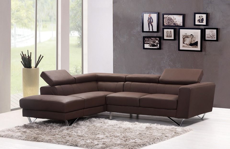 Modern L-shaped brown leather sectional sofa with adjustable headrests on a shag rug.