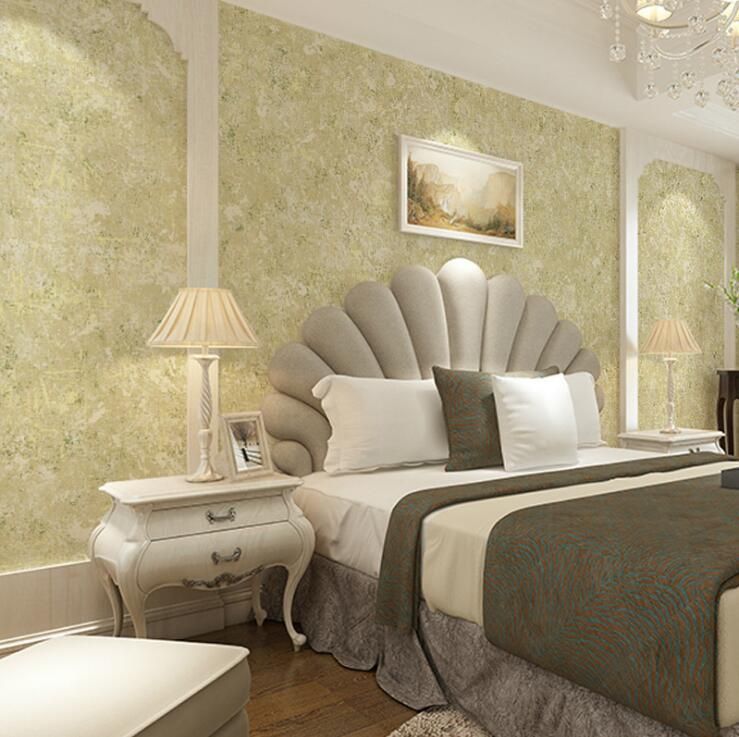 Elegant bedroom featuring a unique scallop-shell headboard, textured green wallpaper, and classic white nightstands.