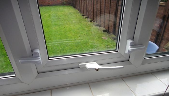 White UPVC window showing a green garden and brown fence outside.